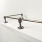 Close-up view of a Black Shadow solid brass corner post and rod assembly mounted on the edge of a white shelf.