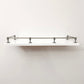 Straight front eye-level view of Black Shadow solid brass gallery railing system mounted on a floating white wall shelf.