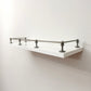 Black Shadow solid brass gallery rail system with corner and middle posts mounted on a floating white wall shelf.