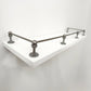 Perspective side view of Black Shadow solid brass gallery rail mounted on a white floating shelf focusing on the front corner post.