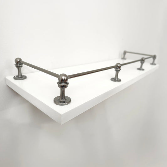 Perspective side view of Black Shadow solid brass gallery rail mounted on a white floating shelf focusing on the front corner post.