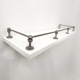 Perspective side view of Black Shadow solid brass gallery rail mounted on a white floating shelf focusing on the front corner post.