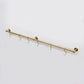 High-angle view of an unlacquered solid brass kitchen hanging rail mounted on a white background with six S-hooks.